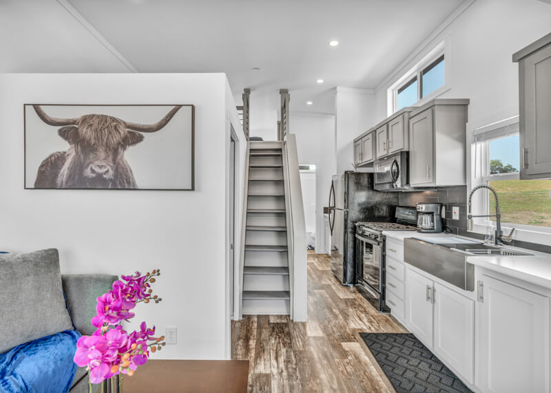 brenham furnished cabin interior with kitchen and stairs to a loft